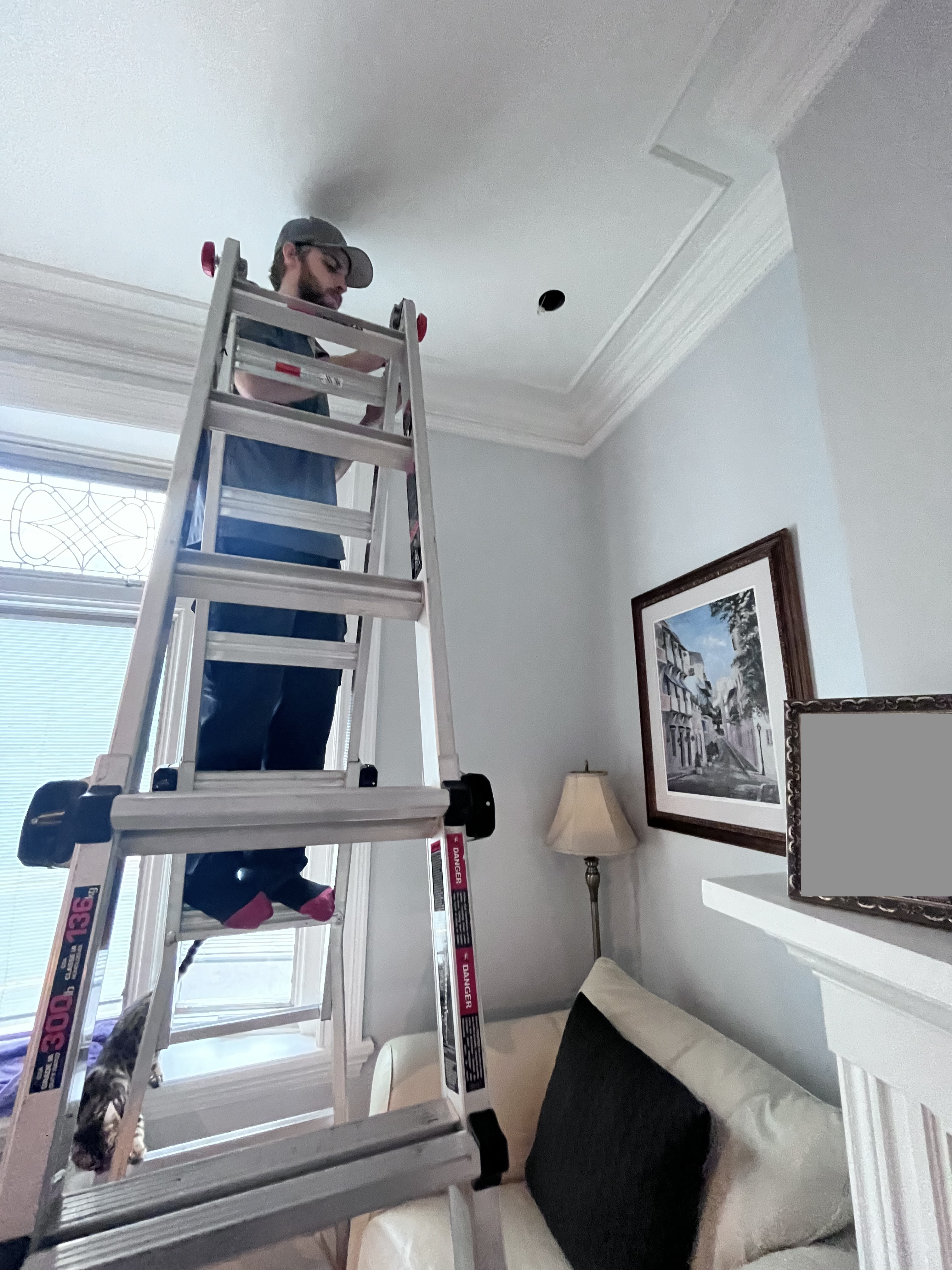 man on ladder repairing ceiling in residential home