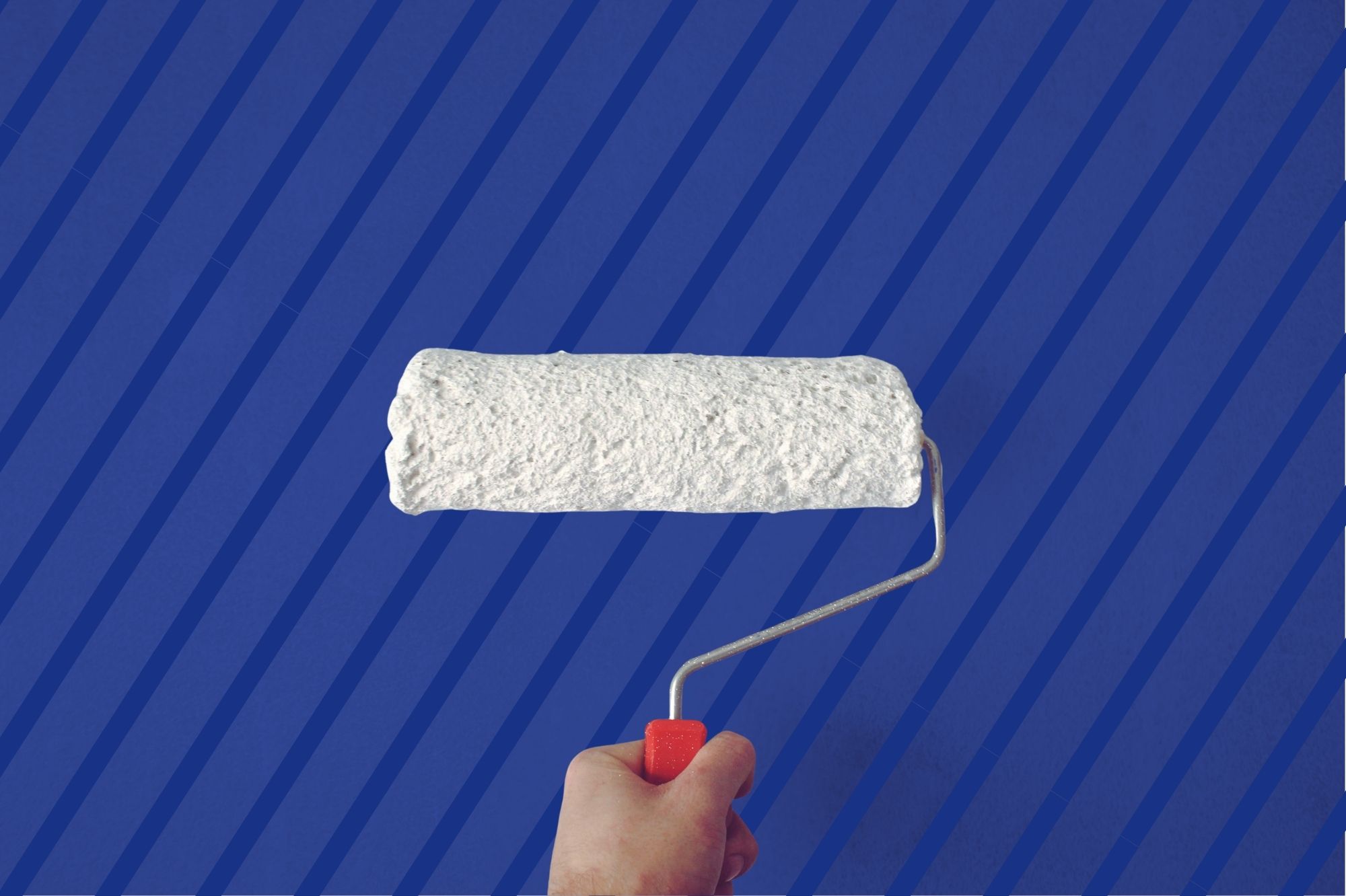 Hand holding paint roller with white paint.